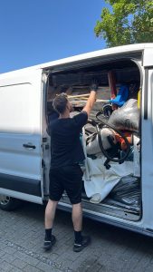 Person beim Verladen von Stühlen, Säcken und Möbelteilen in einen Transporter